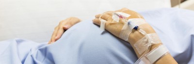 Schwangere mit Kanüle an der linken Hand