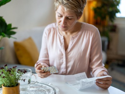 Frau hält Tabletten-Blister und Beipackzettel in der Hand