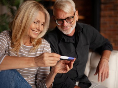 Paar schaut glücklich auf Schwangerschaftstest