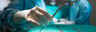 Eine Pinzette wird vom Tisch genommen während einer OP