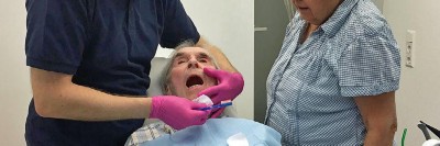 Versorgung eines älteren Patienten in Rückenlage auf Zahnarztstuhl