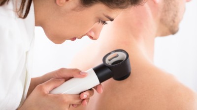 Ärztin untersucht Haut eines Patienten