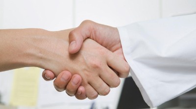 Hand ohne Kittel schüttelt Hand mit Kittel