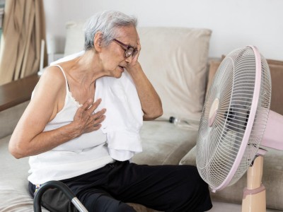 Unter Hitze leidende ältere Frau mit Ventilator