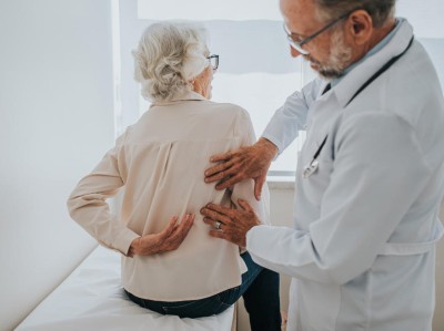 Arzt klärt Rückenschmerz bei älterer Patientin ab