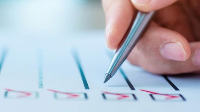 Hand mit Kugelschreiber über einer Checkliste