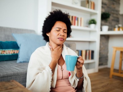 Frau fasst sich an den Hals