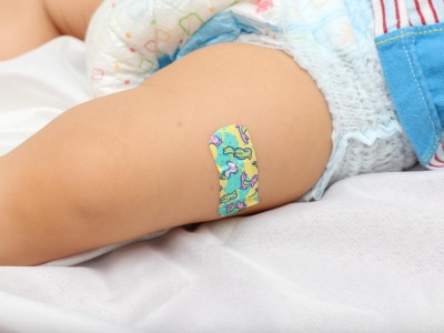 Säugling mit Pflaster am Oberschenkel nach Impfung