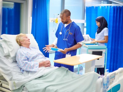 Patientin im Klinikbett spricht mit Arzt