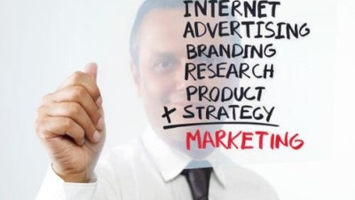 Geschäftsmann hält eine Liste mit Schlagwörtern zum Thema Marketing in die Höhe. 