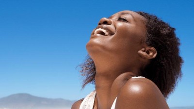 Frau in der Sonne vor blauem Himmel