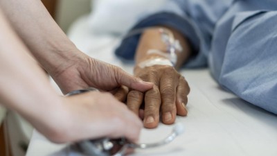 Pflegerin hält Hand von schwerkrankem Patienten