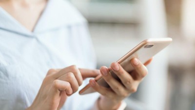 Frau nutzt Smartphone auf einer Rolltreppe
