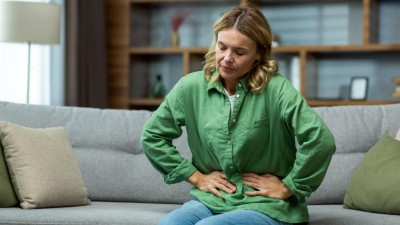 Frau mit Schmerzen sitzt auf Couch