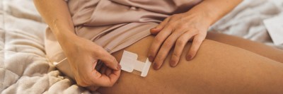 Frau setzt sich ein Pflaster auf den Schenkel