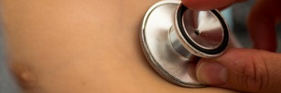 Kind wird mit Stethoskop am Herzen abgehört