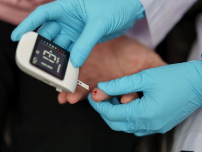 Arzt misst Blutzucker per Glucometer