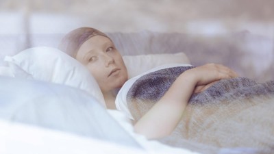 Nachdenkliche junge Krebspatientin liegt im Bett