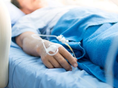Close-up of IV line in the hand of a patient lying in a hospital bed