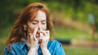 Frau benutzt Nasenspray