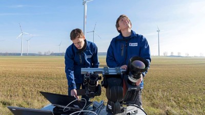 Zwei Männer in einem Feld mit Windrädern.