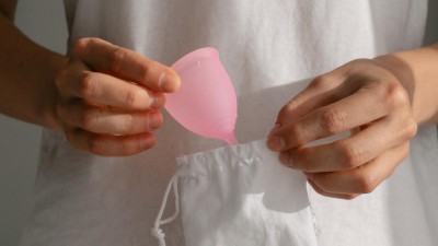 Frau holt Menstruationstasse aus Beutel