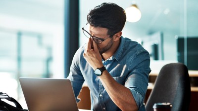 Erschöpfter Mann vor Laptop