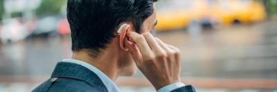 Mann berührt sein Hörgerät