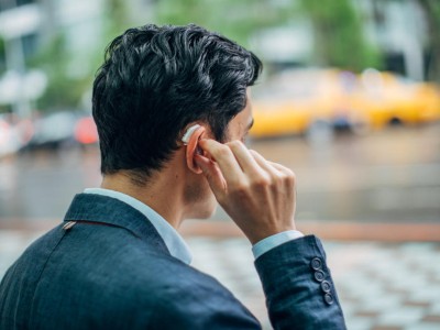 Mann berührt sein Hörgerät