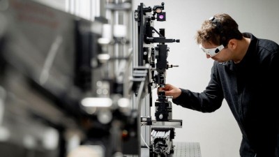 Ein Mann mit Schutzbrille vor einem komplexen Gerät. 