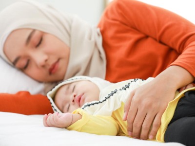 Schlafende muslinische Mutter mit Baby (Symbolbild mit Fotomodellen)