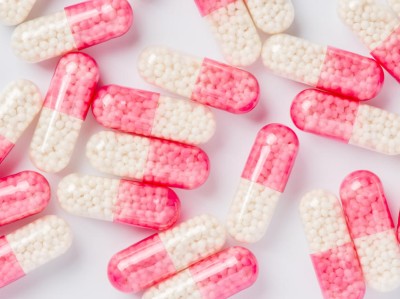 A photograph of half-pink and half- clear transparent capsules on a white background