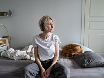 Frau sitzt auf eine Bett und schaut zur Seite