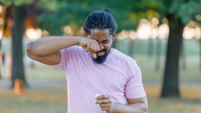 Mann im Park reibt sich die Augen