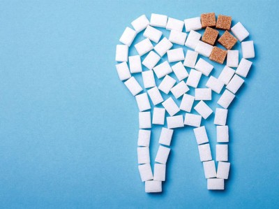 Zahn aus Zuckerwürfeln mit brauner Stelle vor blauem Hintergrund