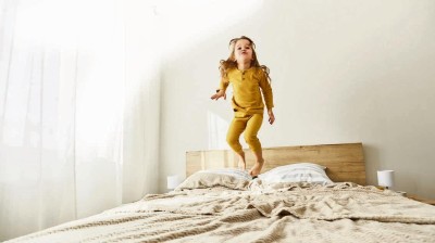 Kind hüpfend auf Bett