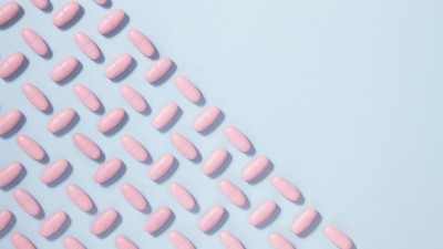 Pink pills on a blue background in diagonal shape