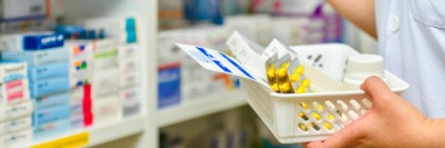 Apothekerin holt Arzneimittel aus Regal