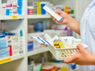 Apothekerin holt Arzneimittel aus Regal