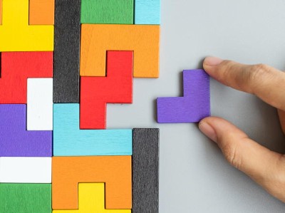 Hand slotting piece into colorful wooden puzzle