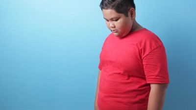Photograph of a boy with overweight / obesity looking unhappy