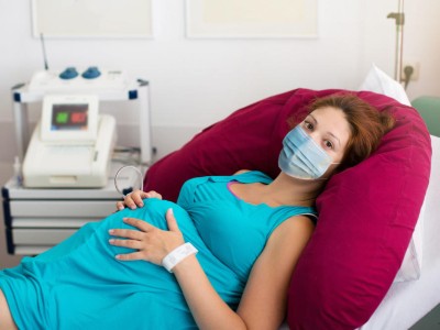 Schwangere Frau in der Klinik mit Gesichtsmaske