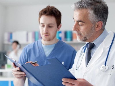 Älterer Arzt mit Arzthelfer schauen über Patientenakte