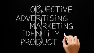 Hand schreibt mit Kreide Begriffe zum Thema Brand (Marke) auf eine Tafel.