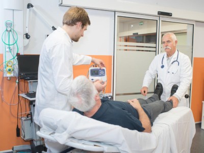 Senior auf Trage spricht mit Arzt und Pfleger