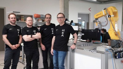 Vier Männer neben einem Roboterarm