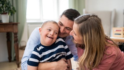 Eltern umarmen ihr Kind mit Down Syndrom