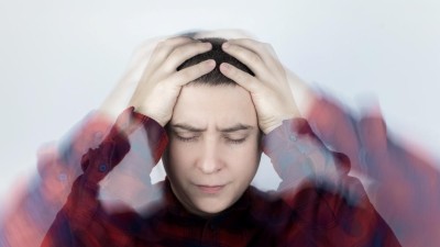 Junger Mann hält sich den Kopf