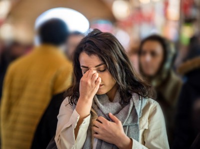 Woman with migraine in a crowd of people