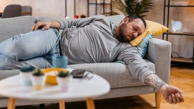 Image is a photograph of a man lying on a sofa